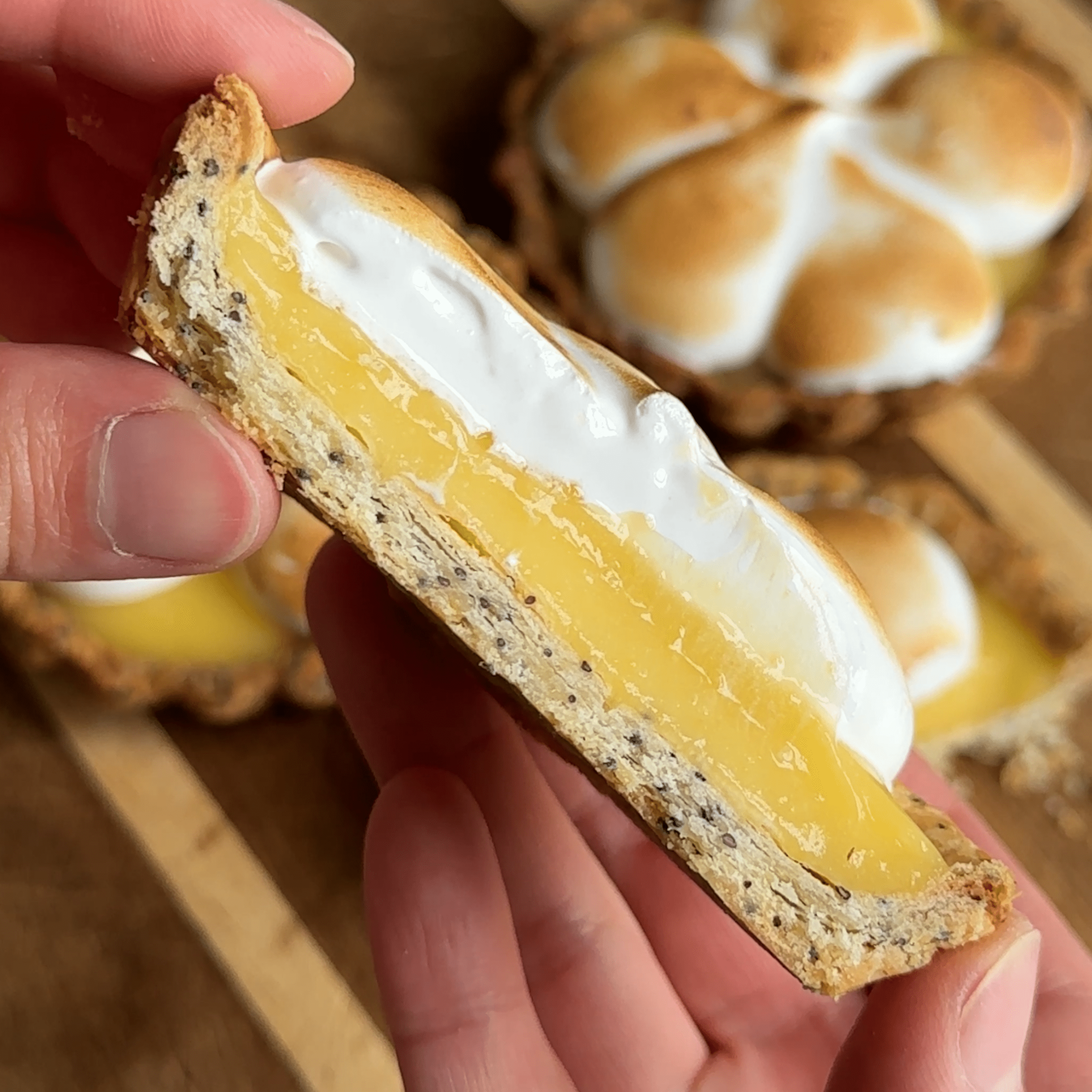 Midsection of a lemon tart with the curd and meringue exposed. The crust is flakey with the layers visible.