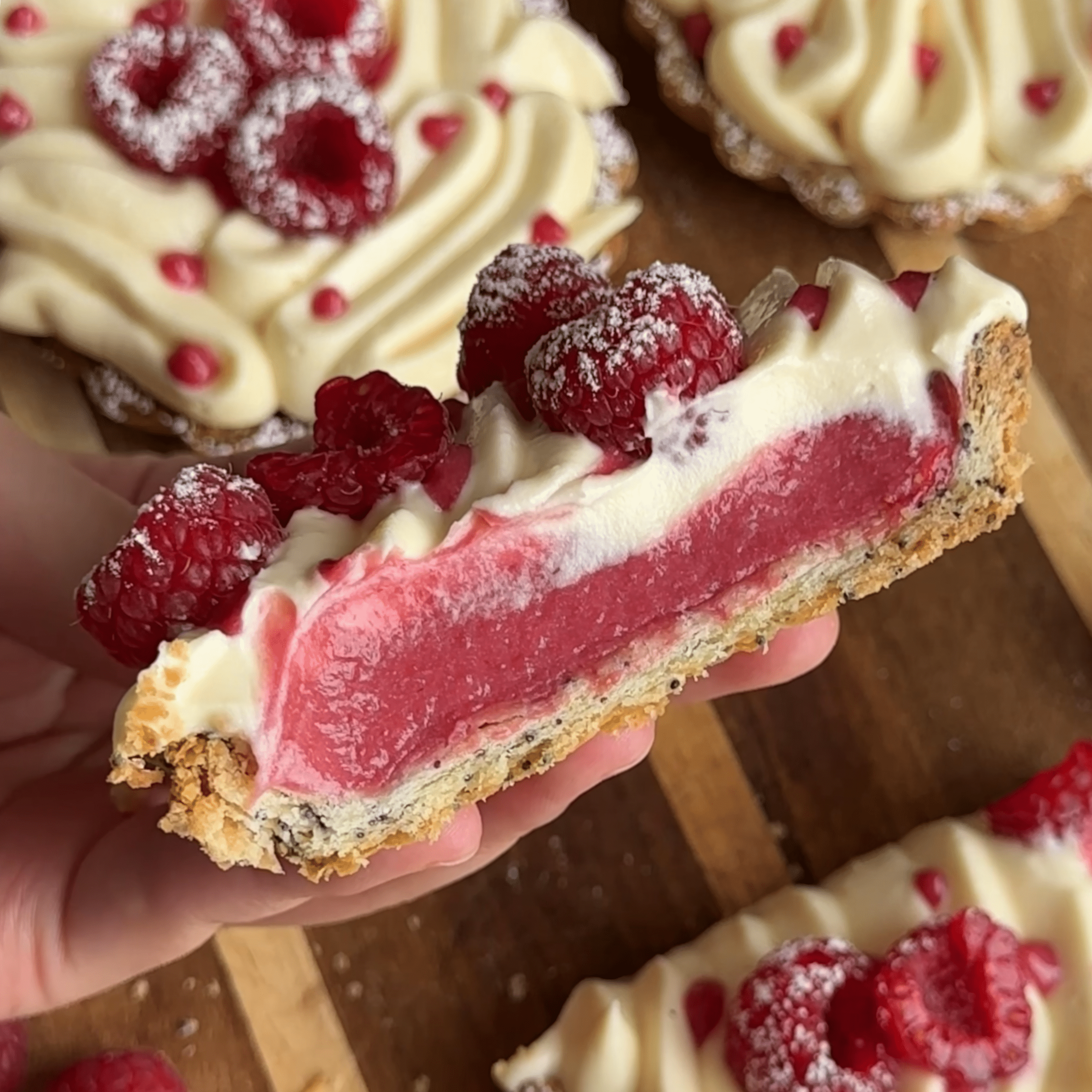 The mid section of a raspberry tart with the pink raspberry curd filling exposed