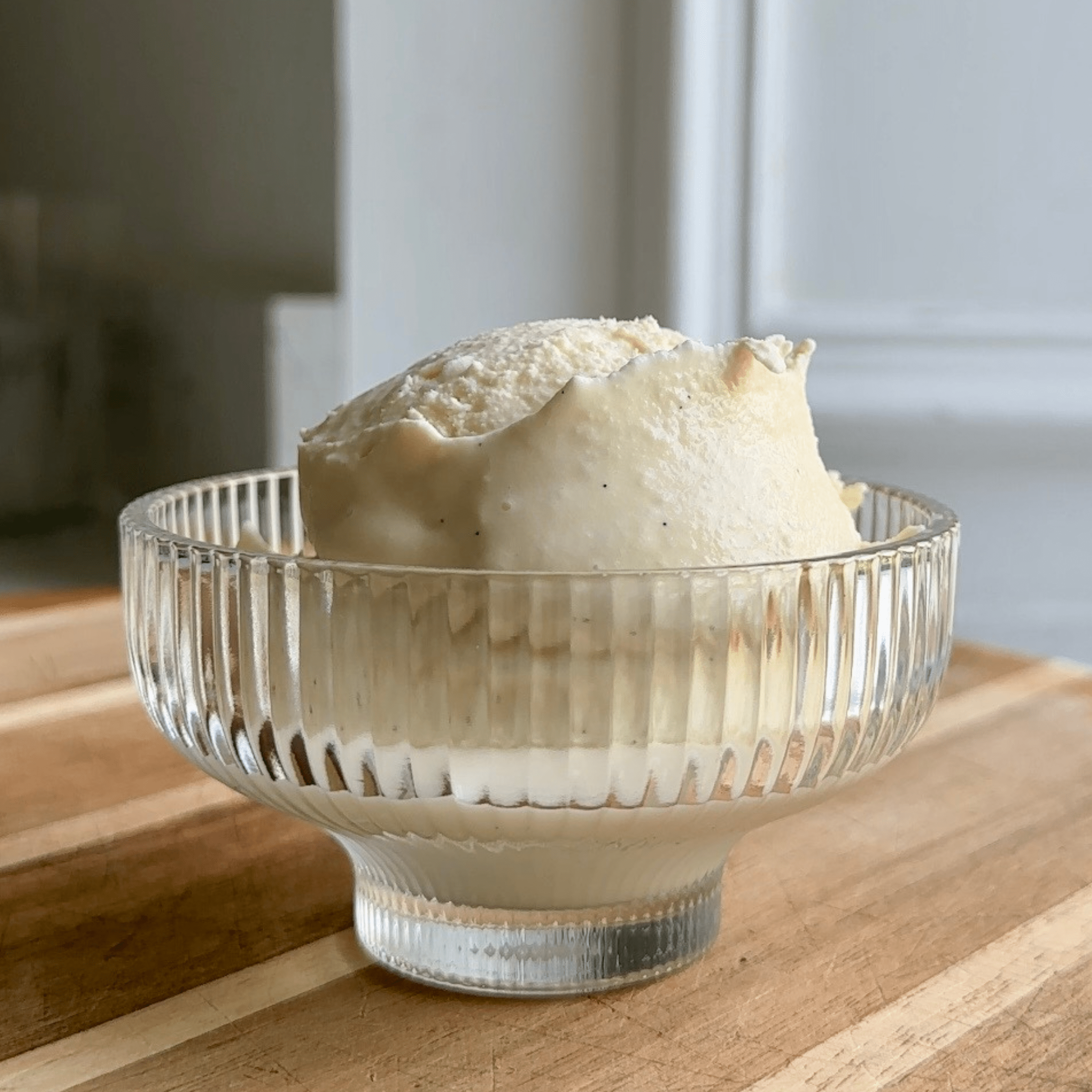 Two scoops of vanilla ice cream in a glass bowl